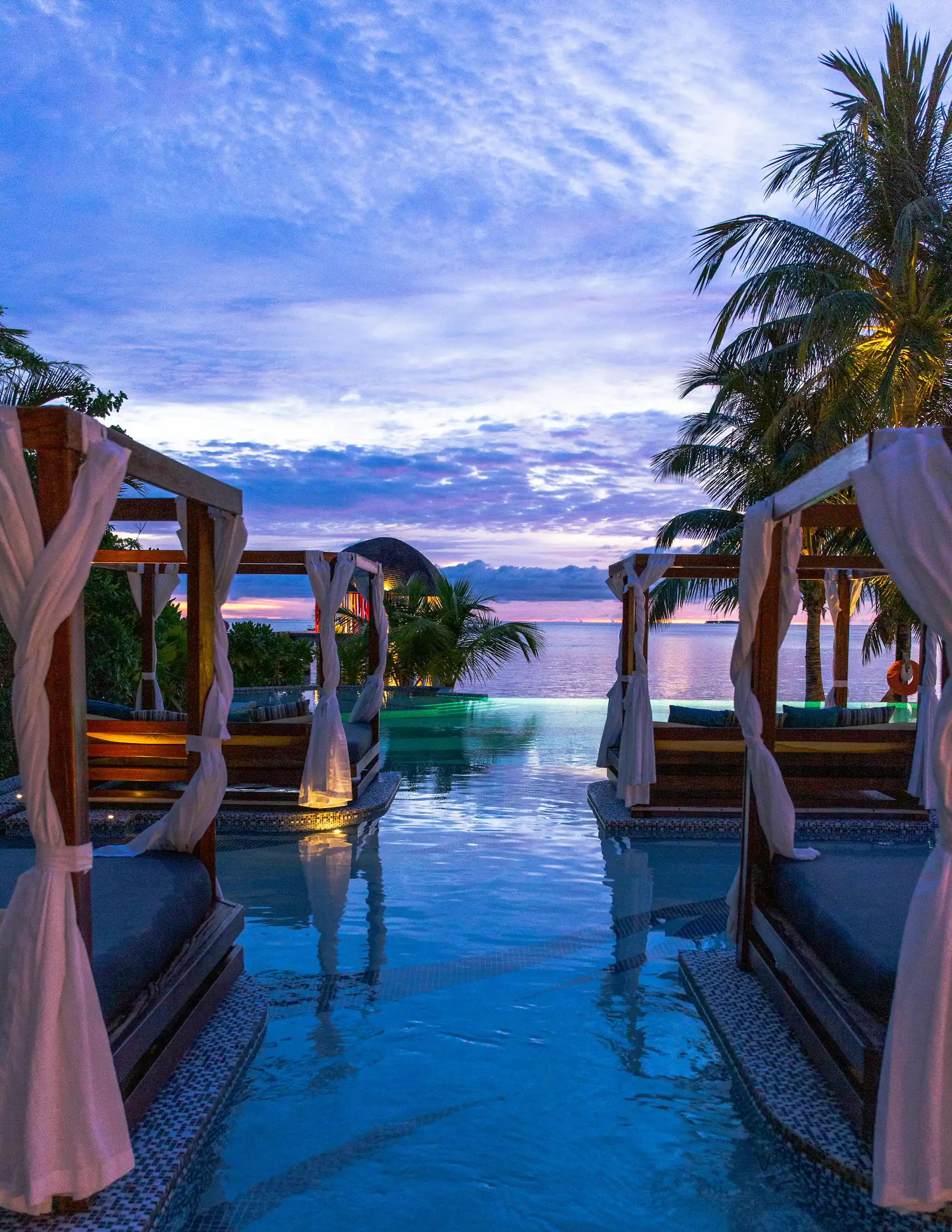 Infinity pool with cabanas at dusk above the ocean