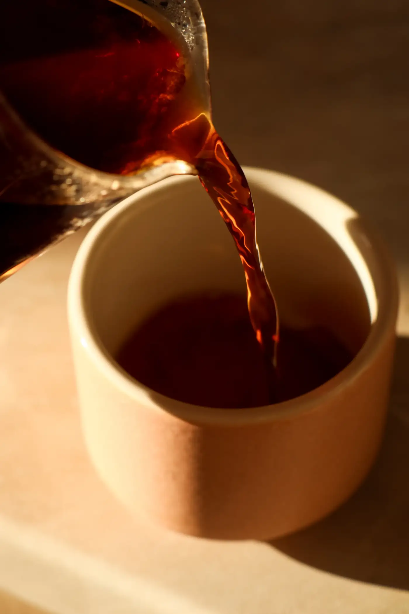 Coffee pouring into a beige ceramic cup