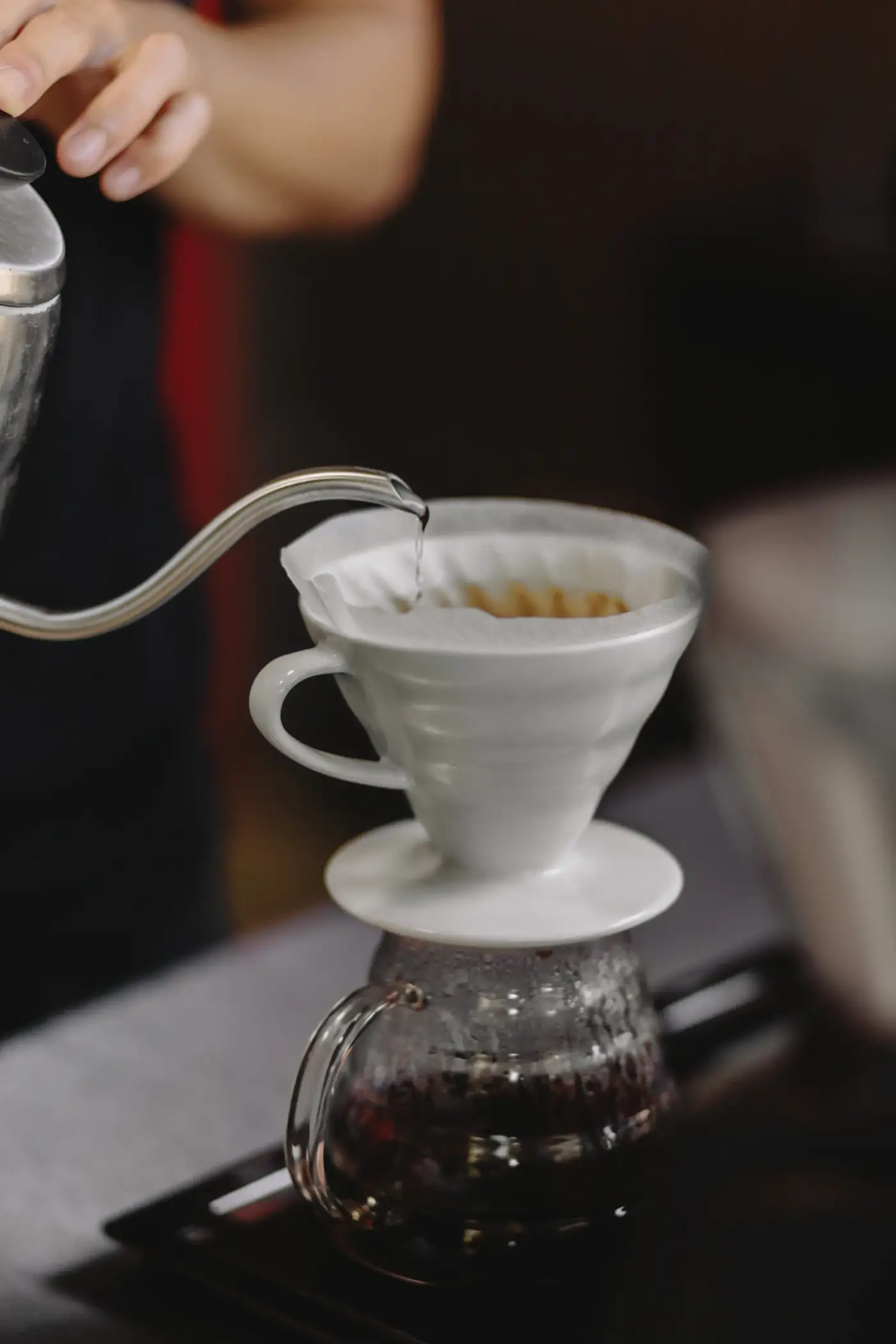 Gooseneck kettle pouring water into a white dripper