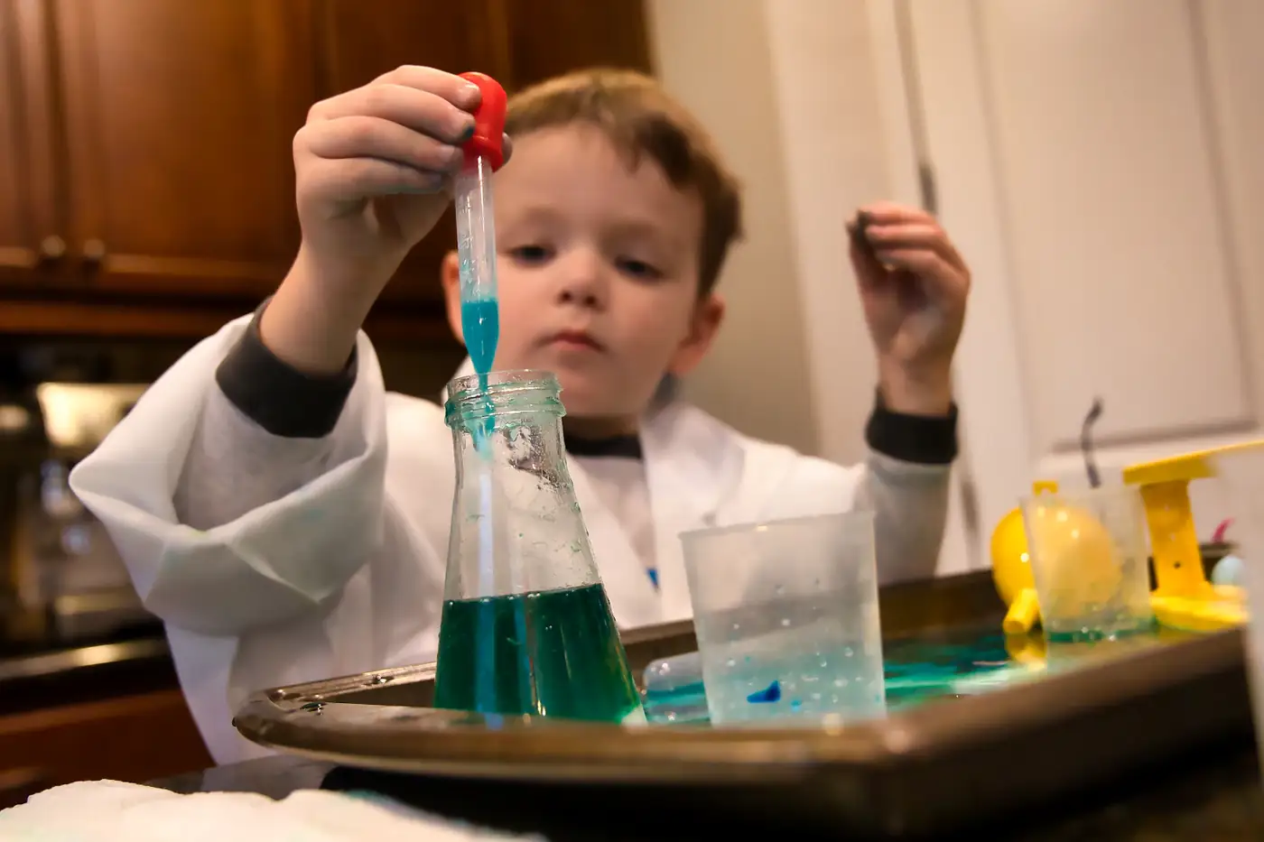 A small boy using a pipette to drop blue liquid