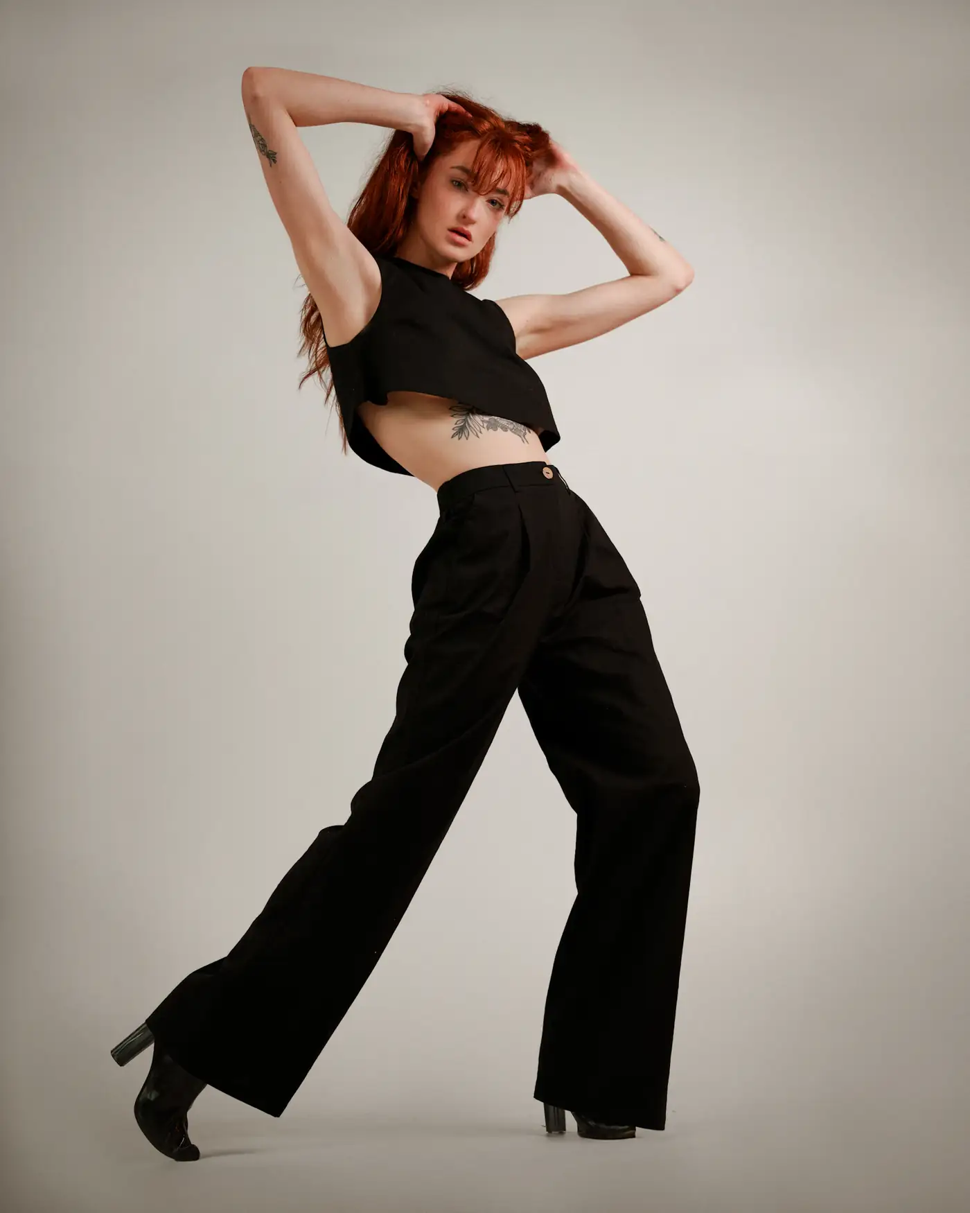 Model in a black crop top and flared trousers in a studio