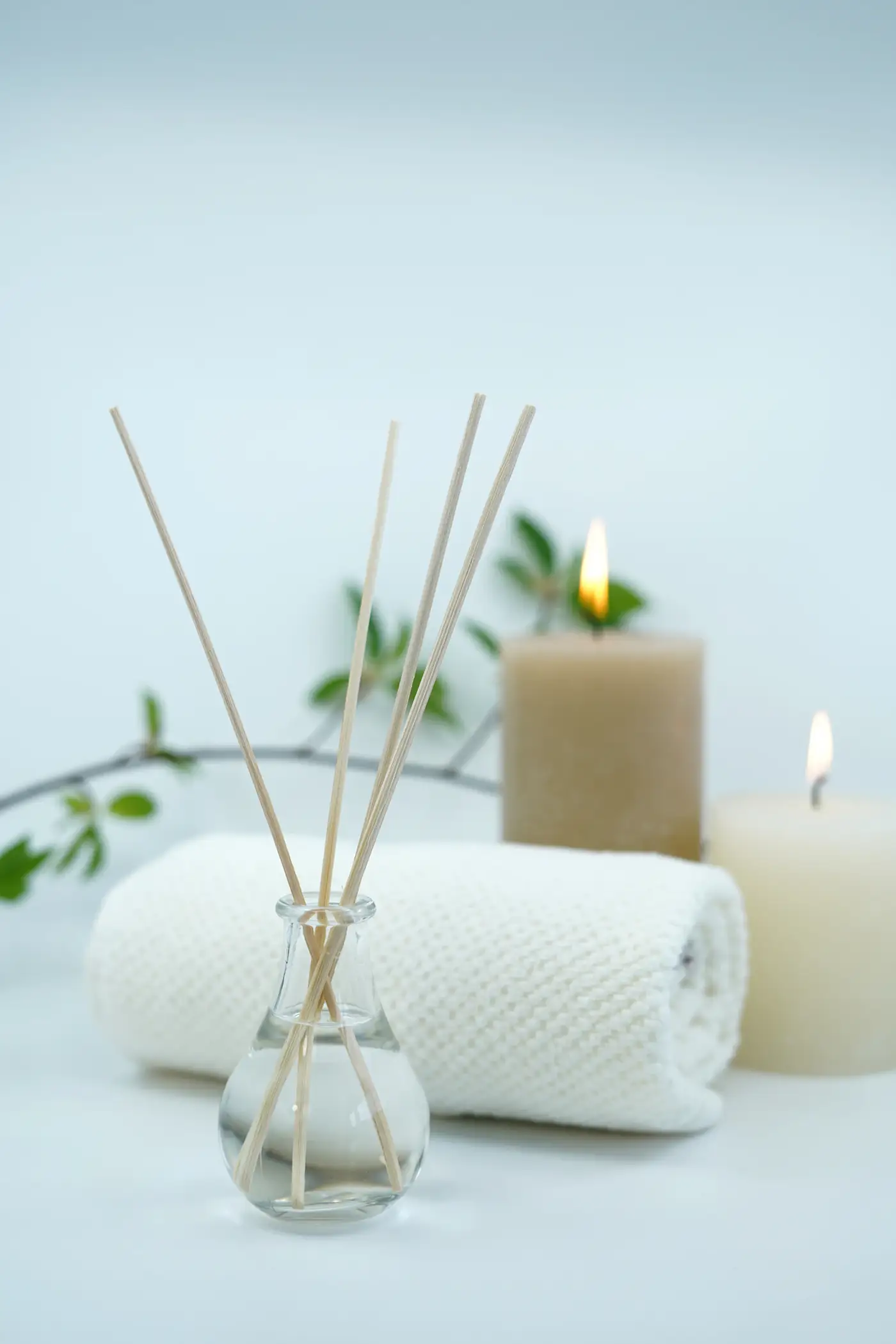 Reed diffuser, candles and a rolled towel