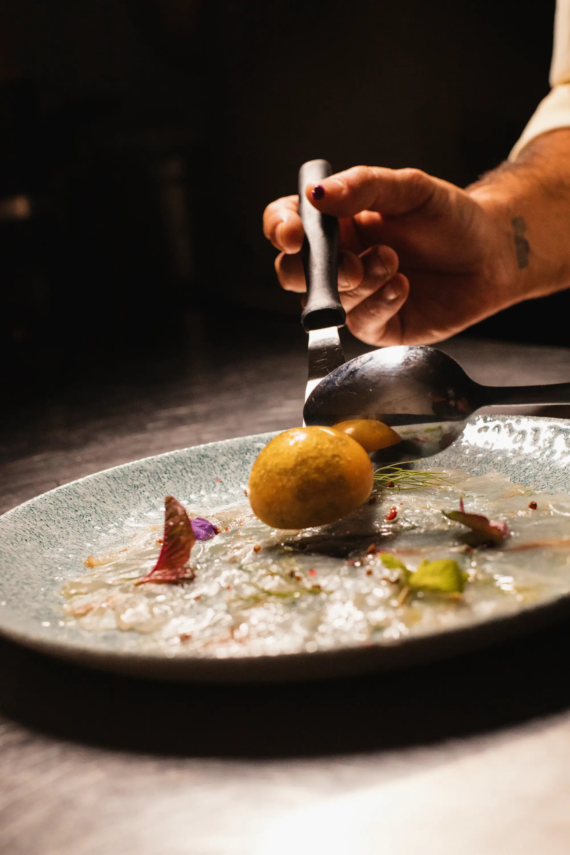 Chef spooning sauce over a plated dish