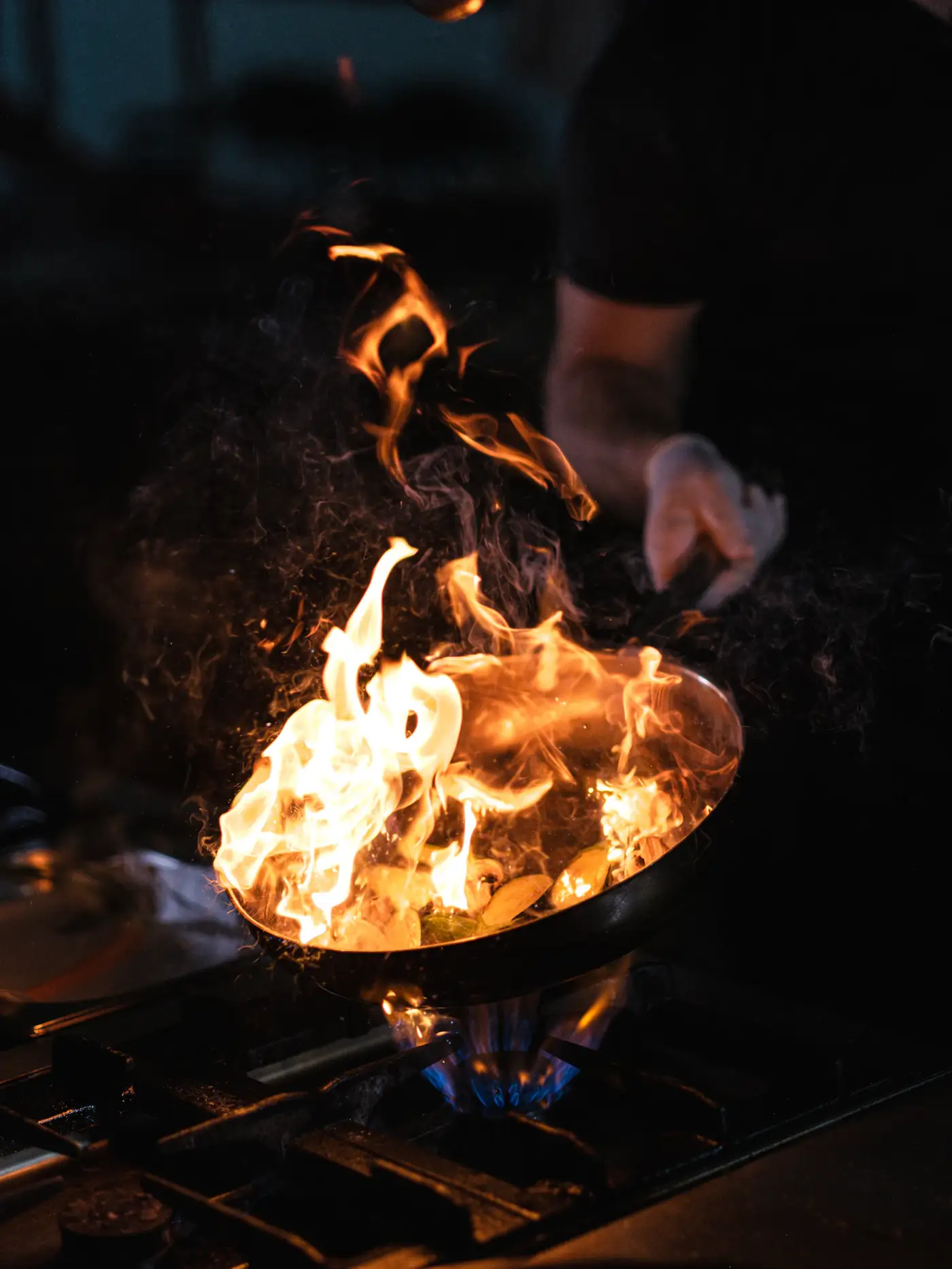 Flames leaping from a pan in a dark kitchen