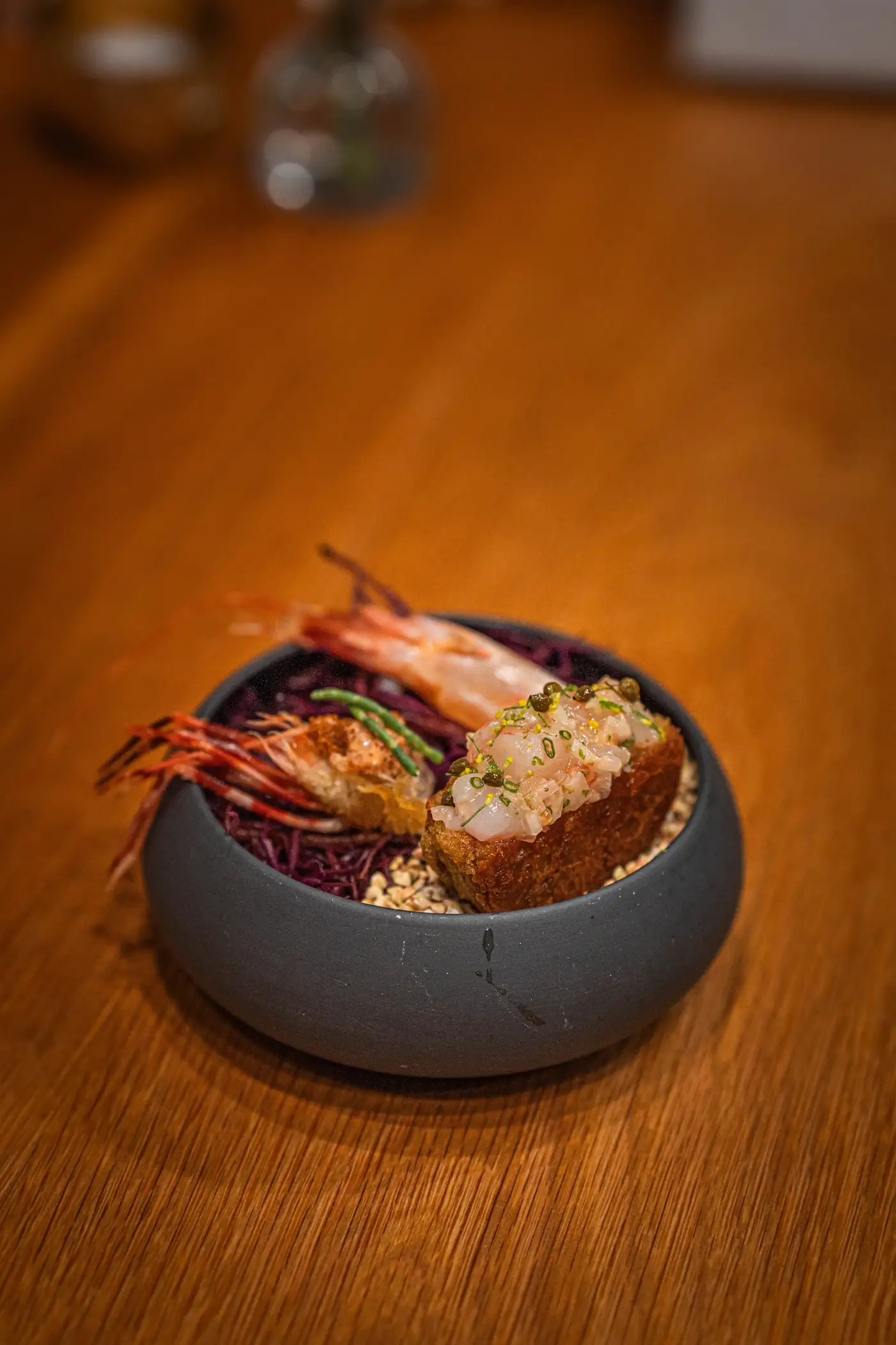Shrimp and fish in a grey bowl on an orange table