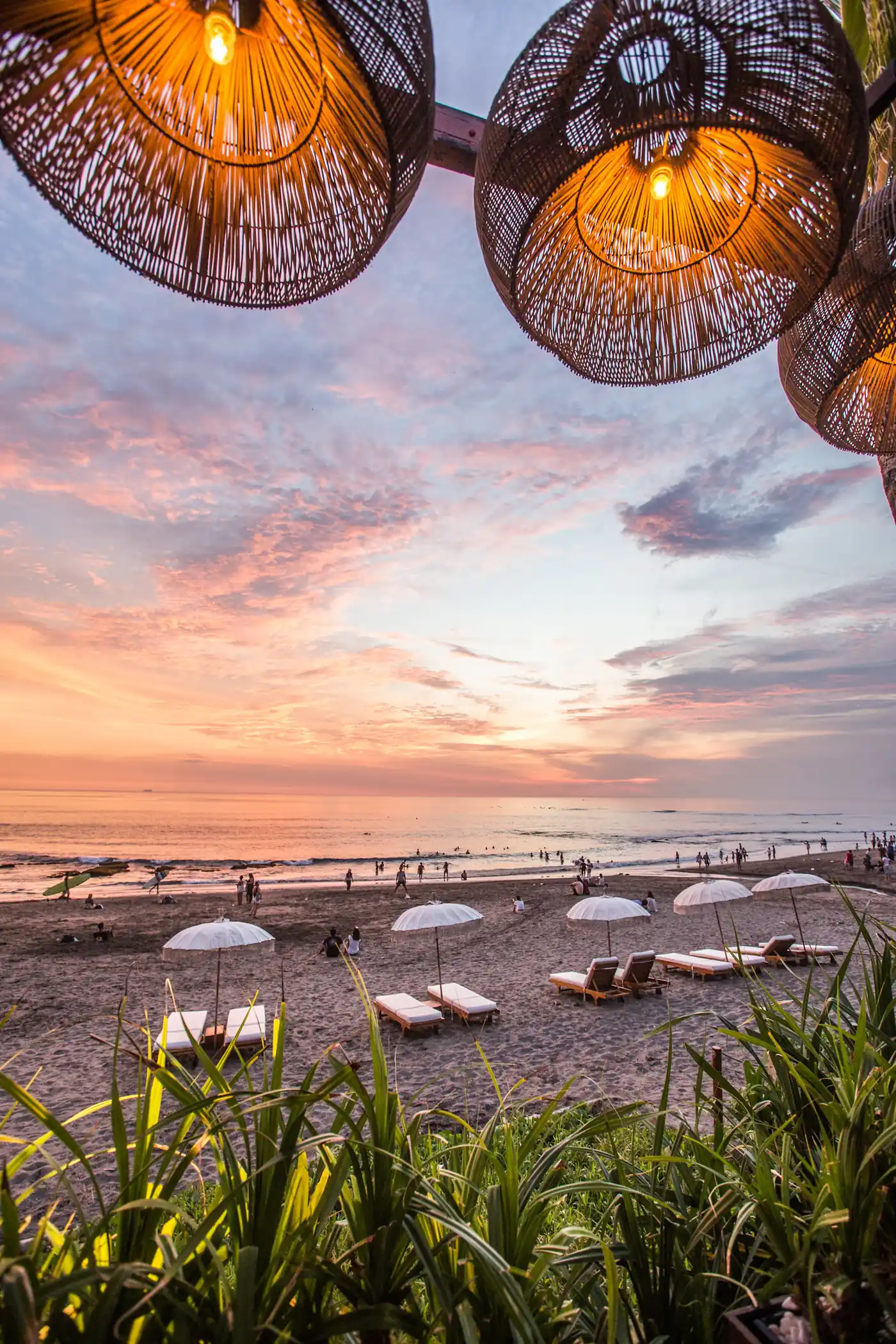 Beach umbrellas and loungers under a pink sunset
