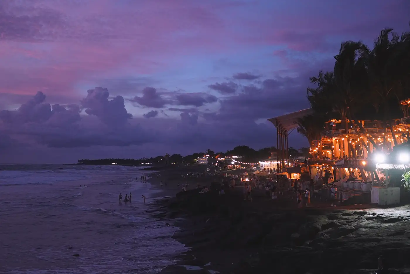 Purple dusk beach with lights along the shore
